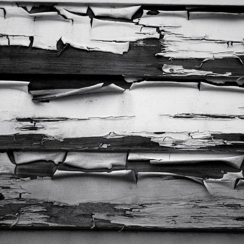 Black and white image of peeling paint on wooden boards