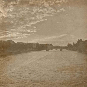Sepia-toned image of a river with a bridge and buildings in the backdrop